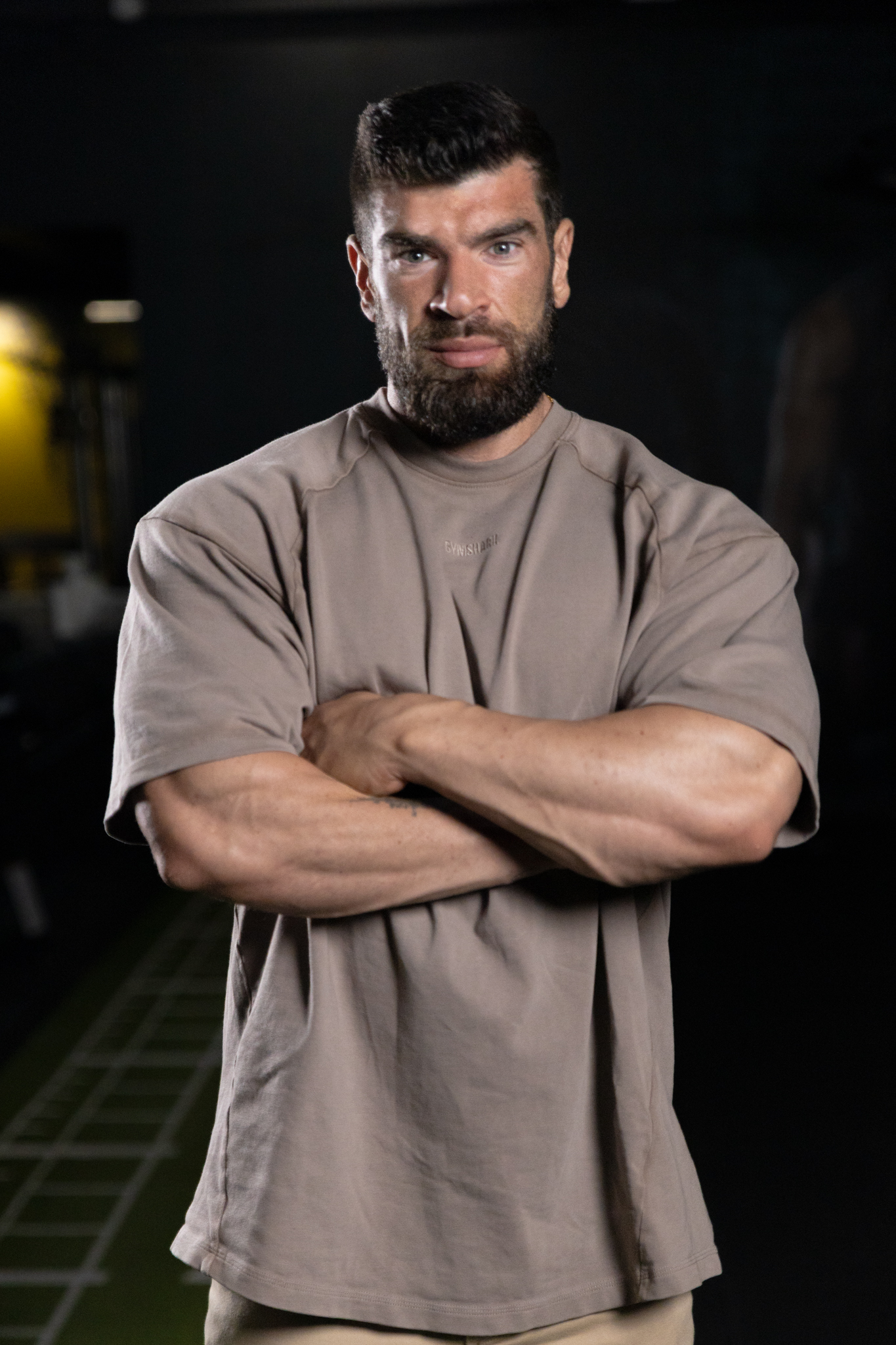Anthony Weiss, mentor business pour coachs, bras croisés dans une salle de sport